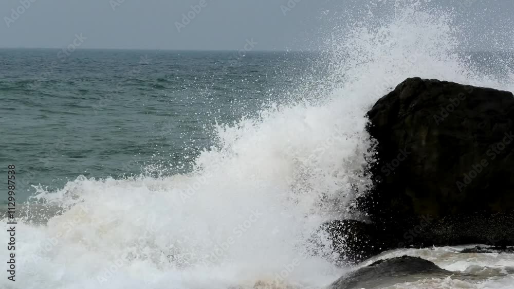 The foam of turbulent waves crashes on the rocks at Kovalam beach in Kerala, India