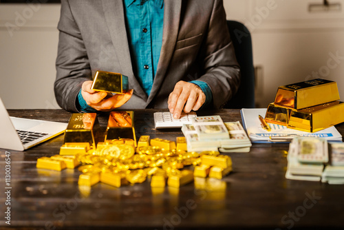 A businessman sits at his desk in a nighttime office, using a laptop to analyze gold bar prices,exchange rates, and investment plans in gold trading, mining,and the stock market amid price increases photo