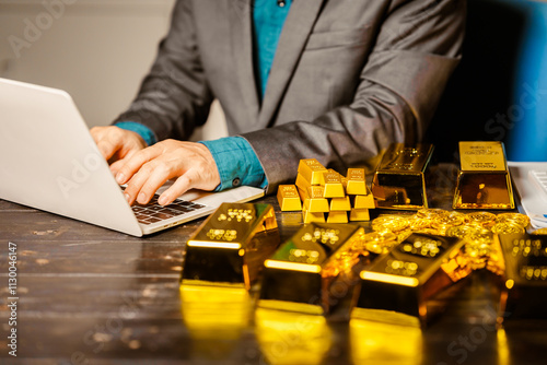 A businessman sits at his desk in a nighttime office, using a laptop to analyze gold bar prices,exchange rates, and investment plans in gold trading, mining,and the stock market amid price increases photo