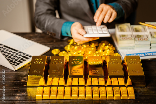 A businessman sits at his desk in a nighttime office, using a laptop to analyze gold bar prices,exchange rates, and investment plans in gold trading, mining,and the stock market amid price increases photo