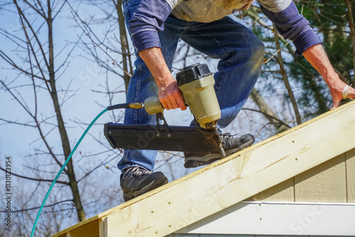 handyman using nail gun to install shingle to repair roof