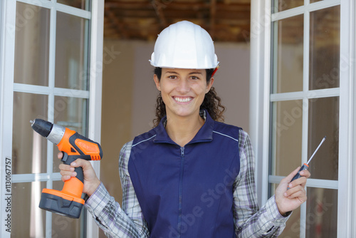 worker woman with drill and screw standing in new home photo