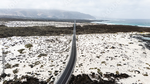 Beautiful coastal road winds through white sand and rocky shores in Mojon Blanco photo