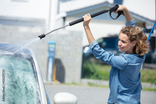 young woman cleaning her car in a self service booth