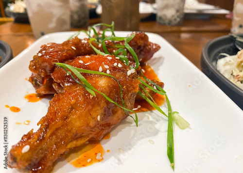 fried chicken in sweet and sour sauce with sesame seeds and fresh herbs in a restaurant