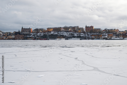 Winter landscape in Stockholm with snowy waterfront and calm water reflections