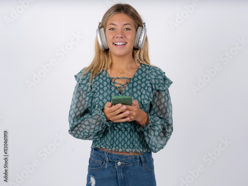 Excited Beautiful teen girl wearing green fashion T-shirt holding smartphone and looking amazed to the camera after receiving good news.