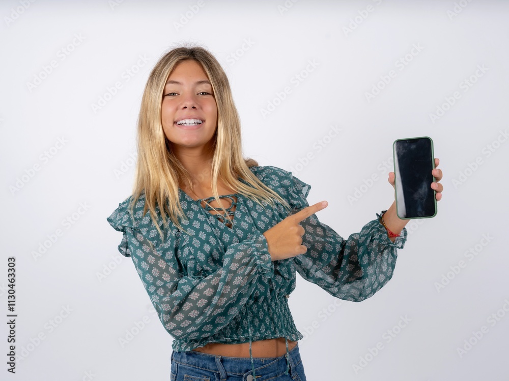 Naklejka premium Attractive cheerful Beautiful teen girl wearing green fashion T-shirt holding in hands cell showing black screen
