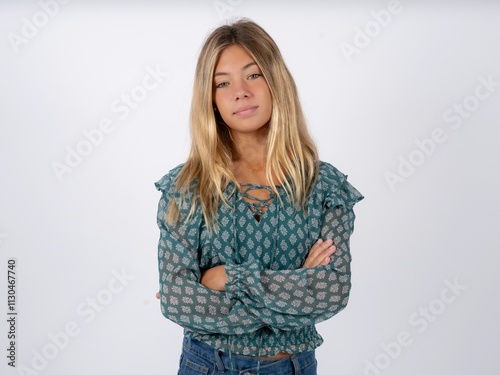 Self confident serious calm Beautiful teen girl wearing green fashion T-shirt stands with arms folded. Shows professional vibe stands in assertive pose.