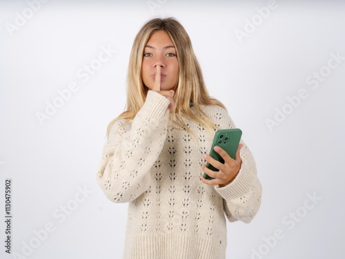 Beautiful teen girl wearing white sweater holding modern gadget ask not tell secrets photo