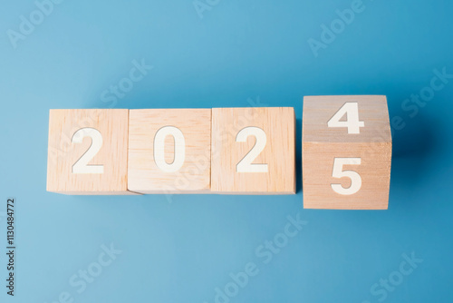 Transitioning from 2024 to 2025, wooden blocks on blue background. Representing the New Year