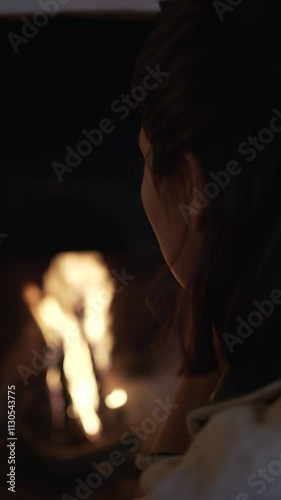 detail of unrecognisable face in front of fire, with firelight on cheek