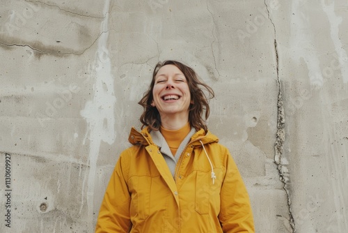 Portrait of a joyful caucasian woman in her 30s wearing a lightweight packable anorak isolated on bare concrete or plaster wall photo