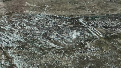 Heavy rain drops on the ground. Raindrops falling on the cement floor on a rainy day. Raindrops on cement floor.