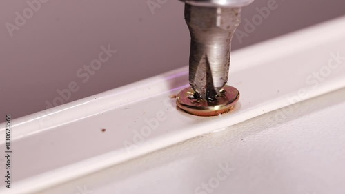 close-up. A screwdriver drill unscrews a screw out of white furniture. repair and manufacture of furniture for home and office. joinery.