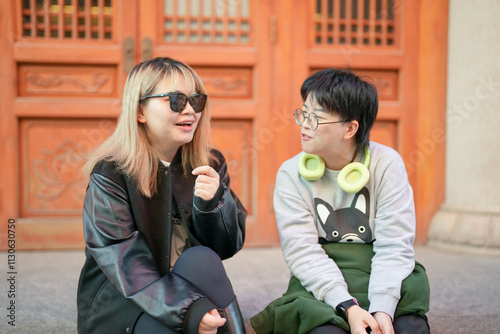 On a cold winter day in December 2024, two Chinese women in their 30s sit and talk in front of a historical building in Jing'an District, Shanghai, China. photo