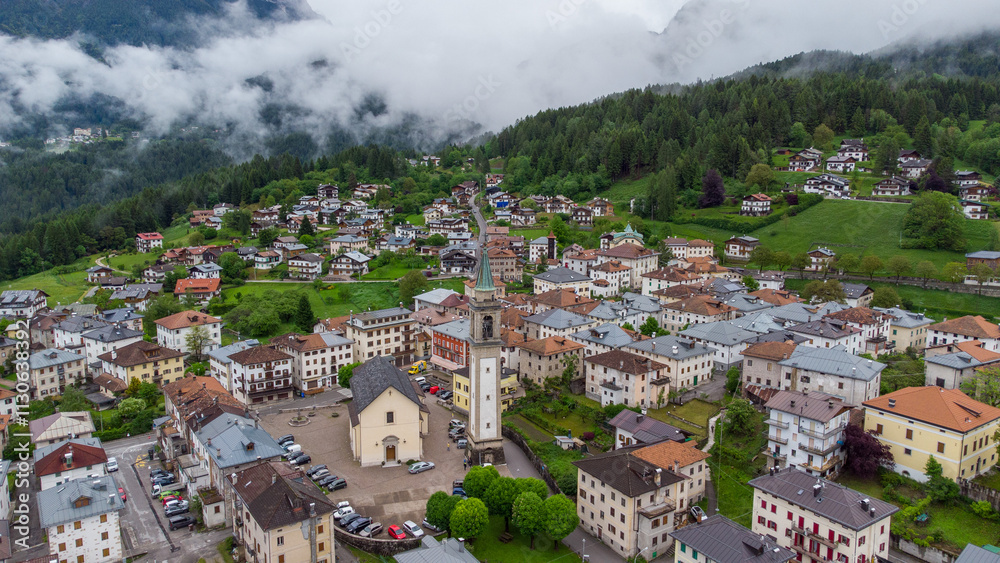 Naklejka premium Mountain Serenity: Aerial View of a Scenic Village Amidst Clouds and Peaks