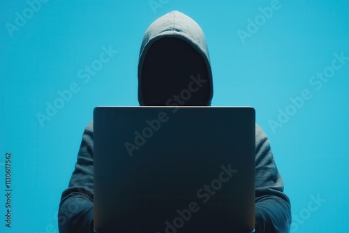 Hacking Vulnerability Laptop Concept. Dark figure in a hoodie working on a laptop against a blue background. photo