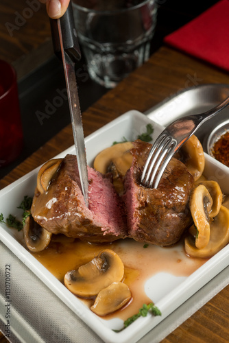 cutting cooked beef fillet with mushrooms