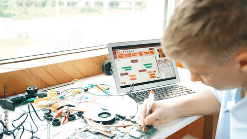 Back view of smart adult repair main board by using electronic equipment on table with laptop with engineering code displayed screen and electronic equipment at STEM technology classroom. Edification. photo