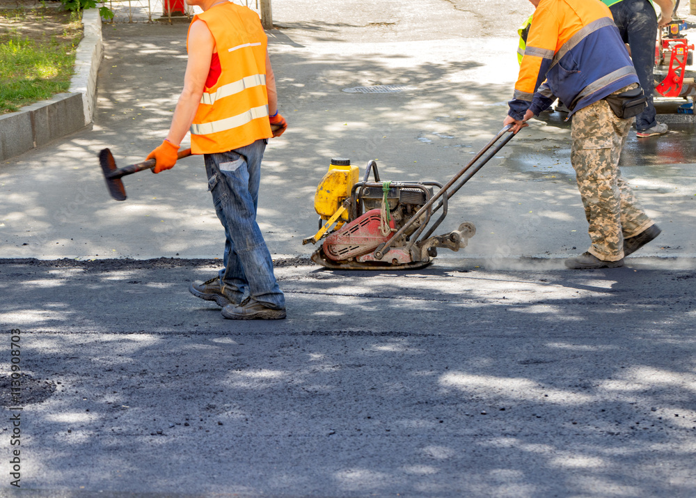 Construction workers skillfully paving a new road on a sunny day with innovative machinery