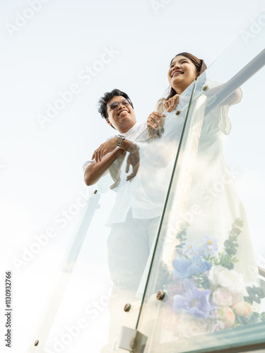 Joyful Asian bride and groom share a romantic moment outdoors, basking in the sunlight sky with scenic view. Their love and happiness radiate, beautiful wedding day and celebration of romance.