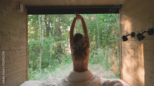 Woman Stretching in Cozy Wooden Cabin with Forest View.