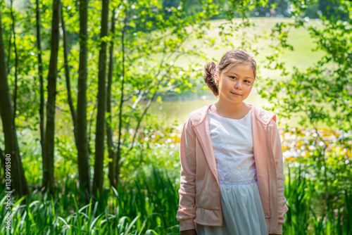 A young school girl in white and pink standing in lush green foliage