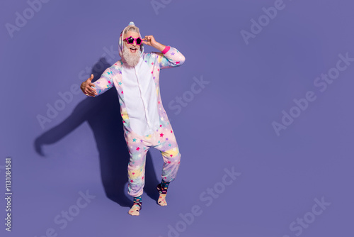 Cheerful man in unicorn pajama posing against purple background for a fun and energizing morning vibe photo