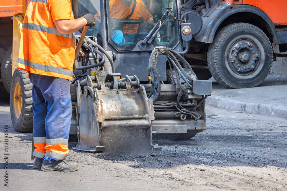 Construction worker repairing the road with heavy machinery in bright daylight