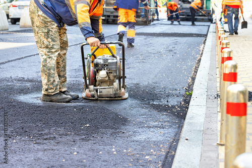 Road construction crew working diligently on a new asphalt surface in an urban setting. Copy space.