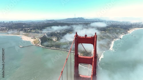Rotating aerial drone shot of a main support on the Golden Gate Bridge, with San Francisco in the background.