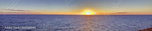 Foto Vivid sunset over a calm ocean horizon, blending vibrant orange and blue hues, e