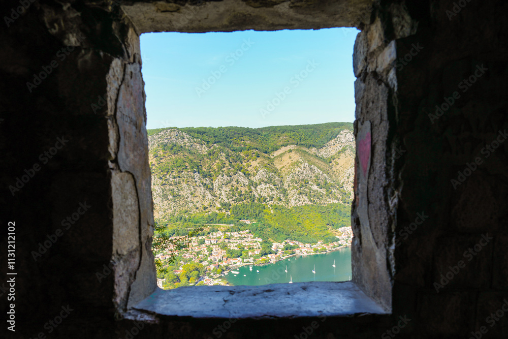 Fototapeta premium View of Kotor through window in stone fortress wall