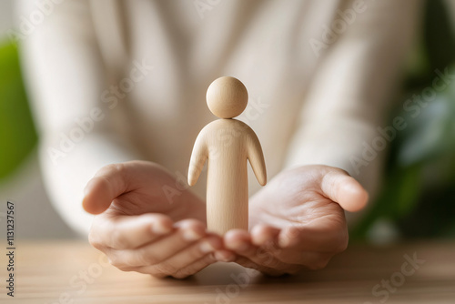 Hands gently holding a small wooden figure representing support care and nurturing with a calm natural background
 photo