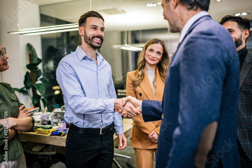 Group of businesspeople standing and shaking hands in a modern office photo