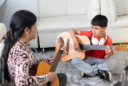 Lifestyle: Boy learning to play acoustic guitar at home