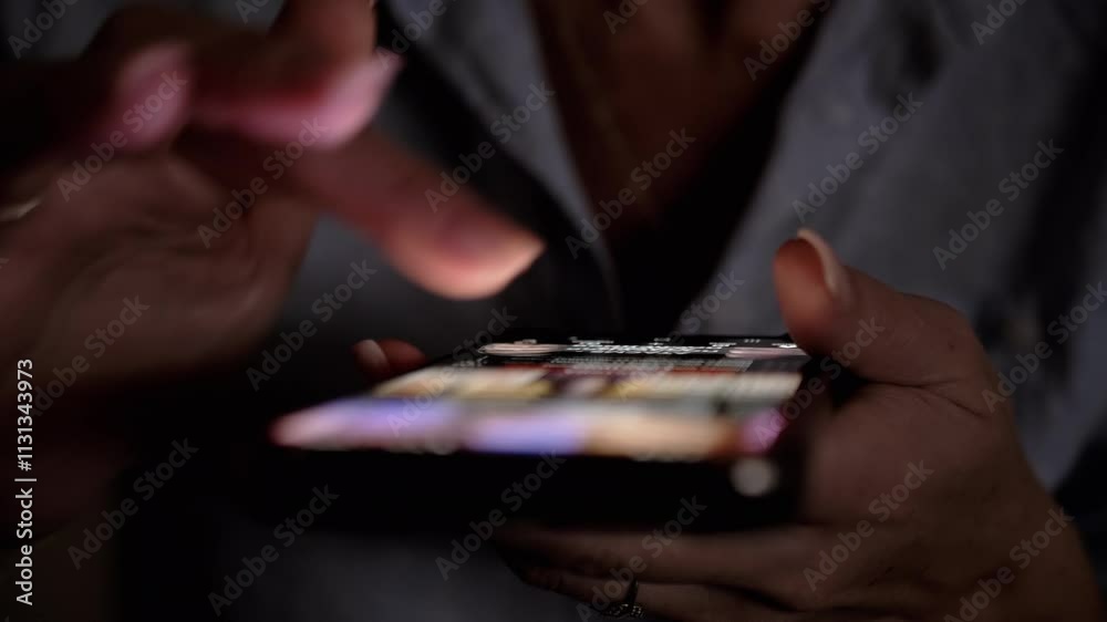 Close-up of a woman's hands scrolling through social media feed on a smartphone in the dark. Perfect for technology, communication, and social media related projects.