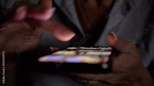 Close-up of a woman's hands scrolling through social media feed on a smartphone in the dark. Perfect for technology, communication, and social media related projects.