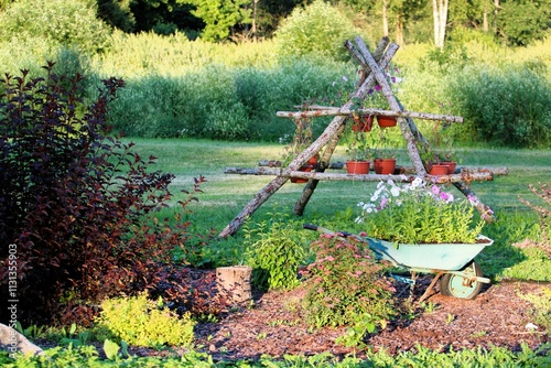 A picturesque garden scene featuring a rustic wooden trellis with flowerpots, an old wheelbarrow repurposed as a planter filled with blooming flowers, surrounded by vibrant greenery