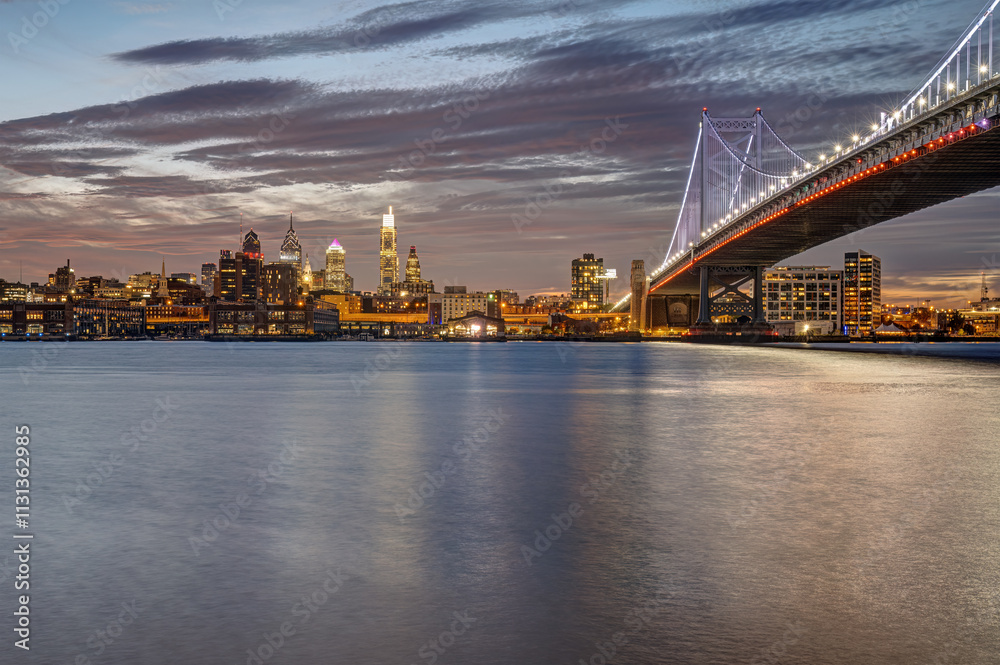 Obraz premium The Benjamin Franklin Bridge an the skyline of Philadelphia with the Delaware River at twilight