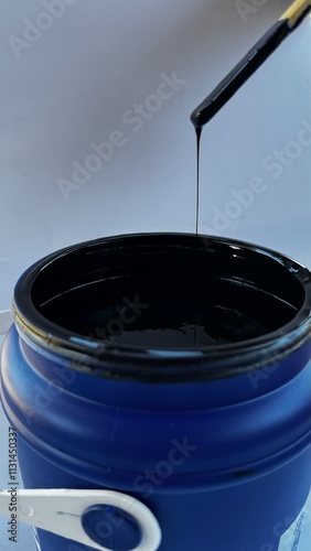 pot of black paint being mixed with a palette