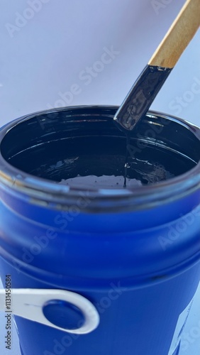 pot of black paint being mixed with a palette