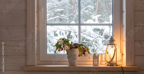 Lamp lantern on the windowsill, winter snowy landscape outside the window. photo