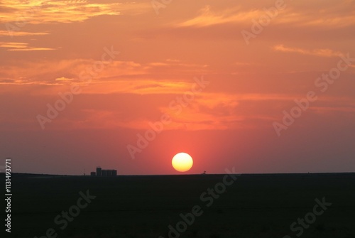 Sunset over the western High Plains prairie in Kansas. The sun setting low in the sky over a Western Kansas farm.