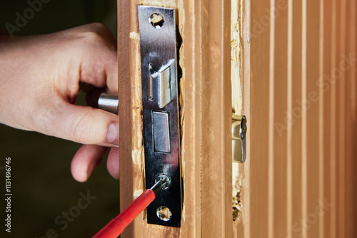 Locksmith inserts framework of mortise door lock into groove or pocket cut into edge of door.