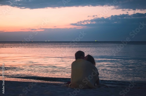Couple sitting on the seashore at sunrise 