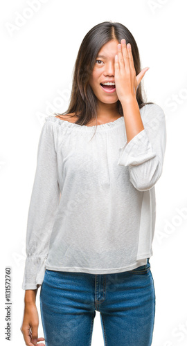 Young asian woman over isolated background covering one eye with hand with confident smile on face and surprise emotion.