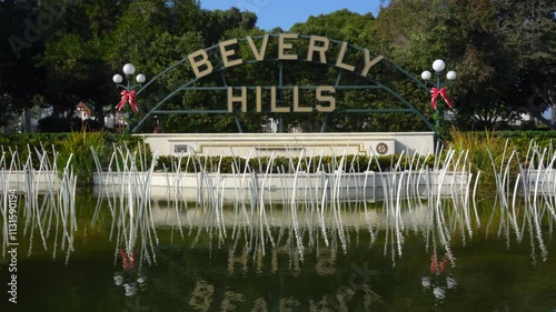 Beverly Hills, California - December 6, 2024: Iconic Beverly Hills sign adorned with festive decorations, surrounded by greenery and reflective water.