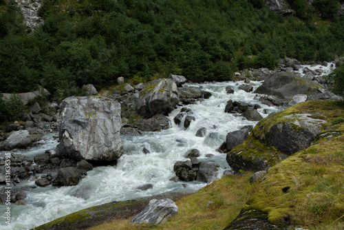 A powerful glacier river flows from the Jostedalsbreen Glacier, cutting through the rugged landscape. The river’s milky turquoise waters, fed by glacial melt photo